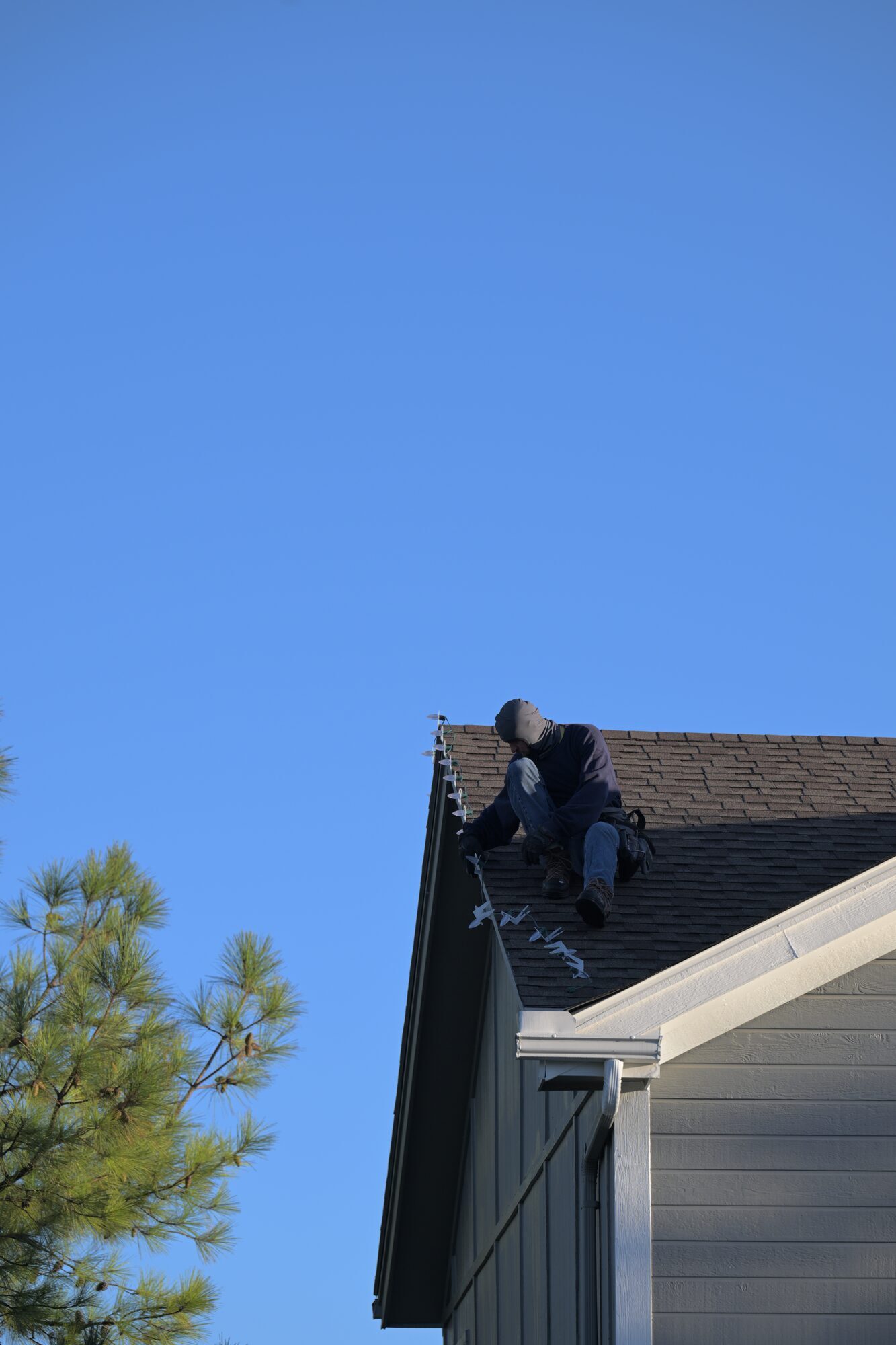 Professional installer attaching Christmas lights to roofline